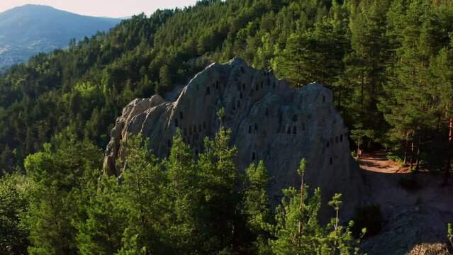 Drone orbiting around a natural rock formation Eagle's Rock Orlovi Skali, jotted with beehive-like trapezoidal niches on Rhodope mountain in Bulgaria.