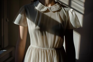 sunlight casting shadow on a dress with a peter pan collar - obrazy, fototapety, plakaty