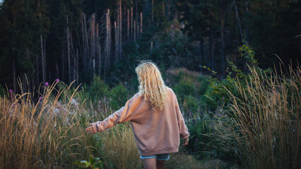 Young Blonde Girl with Hoodie Walking in Dark Forest - 768612369
