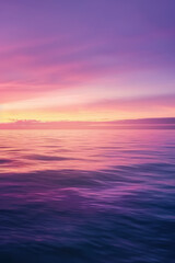Obraz premium Tranquil seascape with smooth water surface and a vibrant sunset sky transitioning from pink to purple hues, reflecting on the calm ocean.