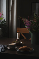 coffee and croissant in rustic country cottage. Cozy evening home interior in brown dark colors