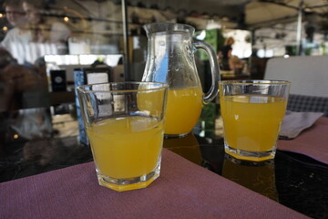 Glasses and decanter with citrus, orange or multivitamin juice on the table.
