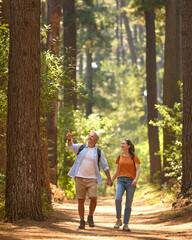 Senior Retired Couple Holding Hands Hiking Along Trail In Countryside - 768619531