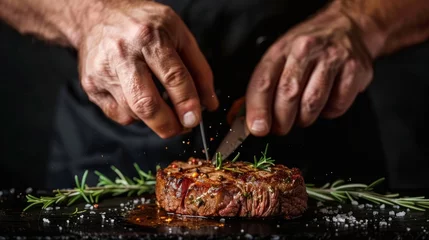 Fotobehang Chef's hands preparing a succulent steak on a black backdrop, leaving room for menu or recipe details. © Firuz