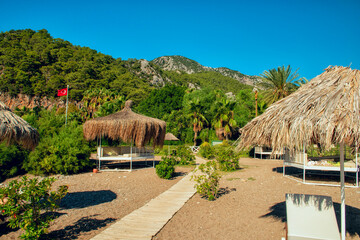 gazebos with reed canopies on a hot beach overlooking green mountains. Relaxation on the beach.