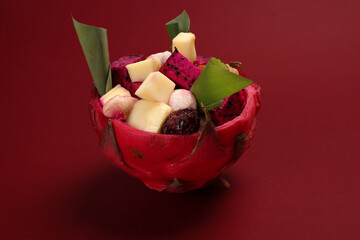 Beautiful Mangosteen mango dragon fruit cube fruit salad in dragon fruit skin bowl on red background - 768621729