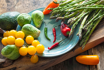branch with yellow cherry tomatoes, asparagus, hot peppers and Brussels sprouts on a wooden board