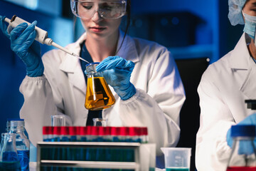 Life scientists researching in laboratory. Focused female life science professional pipetting...