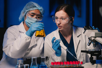 Life scientists researching in laboratory. Focused female life science professional pipetting...