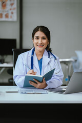 Female doctor sitting at a desk, looking at the camera.
