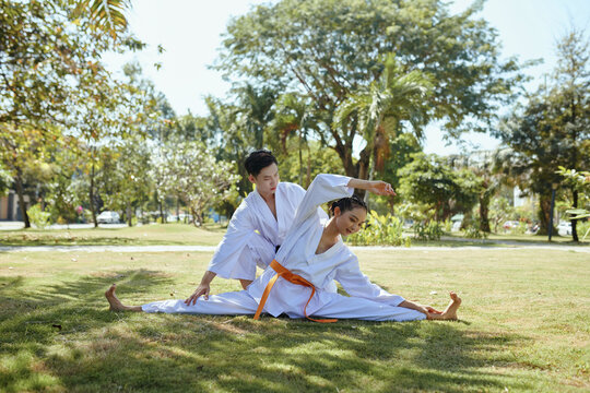 Taekwondo coach controlling girl doing splits and doing side bend