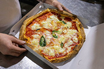 Pizza Margherita tradizionale napoletana con pomodoro, mozzarella e basilico mentre viene sistemata...