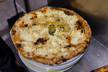 Pizza tradizionale napoletana con provola, pepe, basilico e tarallo sbriciolato appena sfornata e pronta per essere servita in una pizzeria