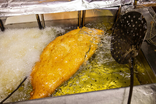 Pizza fritta tradizionale napoletana ripiena di ricotta, pepe e cicoli di maiale mentre viene fritta nell'olio bollente 