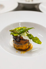 Parmigiana di melanzane guarnita con stracciata di bufala e basilico fritto pronta per essere servita come seconda portata di un evento in un ristorante