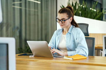 In an office setting, a professional woman in a light blue blouse engages attentively with her...