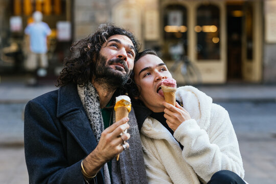 Gay couple eating an ice cream cone while relaxing outdoors.