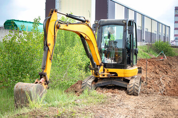 A excavator aggressively excavating soil in a field, creating a path through the earth