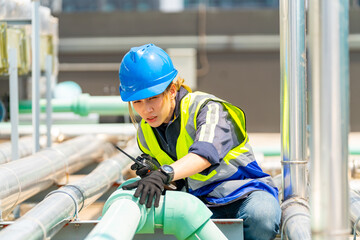 Asian woman engineer in safety uniform working and speaking on two way radios at outdoor...