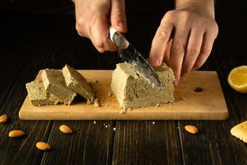 Slicing sunflower halva. A knife in the hands of a chef for cutting halva on a cutting board for...