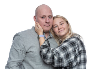 Dad and adult daughter smile and hug. A bald man in a gray shirt and a pretty blonde teenager in a black and white checkered shirt. Love and tenderness in relationships.