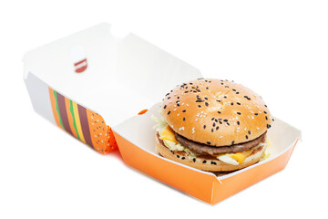 Appetizing burger in craft paper packaging. Delicious garbage food. Isolated on a white background. Close-up.