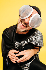 Man Dressed in Creative Fly Costume With Oversized Glasses Smiling Joyfully Against Yellow Background