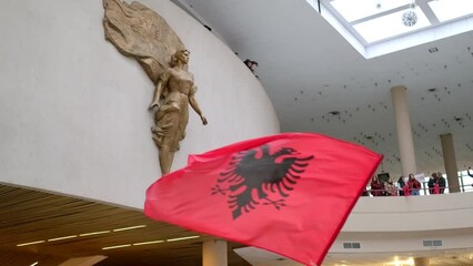Tirana, Albania - November 28 2023: Within the Tirana Congress Hall, a vibrant Albanian flag waves, commemorating Independence Day, with the statue of Mother Teresa as a silent witness