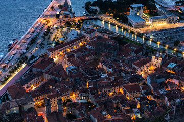 Aerial view of Kotor Old Town at twilight, warm lights contrast against the cool dusk shades over stone buildings. Montenegro - obrazy, fototapety, plakaty