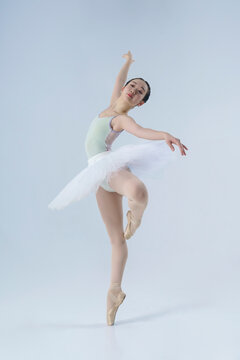 young Japanese ballerina poses in a photo studio with ballet elements showing stretching and plasticity