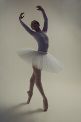 young Japanese ballerina poses in a photo studio with ballet elements showing stretching and...