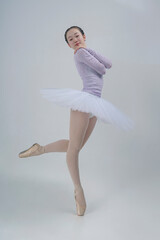 young Japanese ballerina poses in a photo studio with ballet elements showing stretching and...