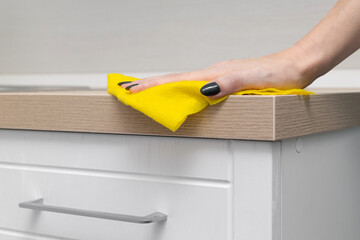 woman wiping kitchen countertop with a rag, close-up. - obrazy, fototapety, plakaty