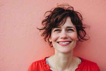 Portrait of a smiling young woman on a pink wall background.