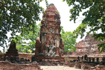 Buddha statue and remains of ruined ancient prang at Wat Mahathat temple in Ayutthaya, Thailand