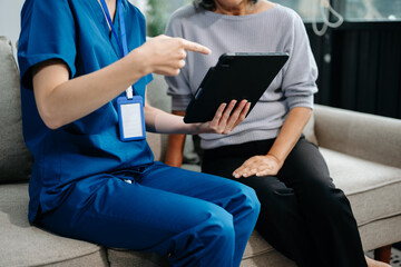 Young nurse helping elderly woman walk in the room, holding his hand, supporting. Treatment and...