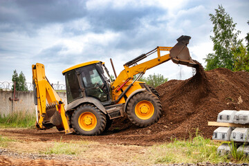 A bulldozer or a loader actively digging into a large pile of dirt at a construction site