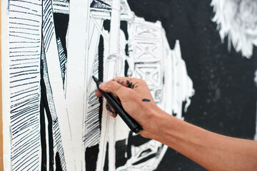Young male painter passionately paints picture with black permanent marker for outdoor street...