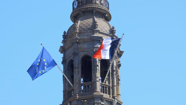 French and european flags on the belfry of the Hotel de Ville, the city hall of Paris, France in summer