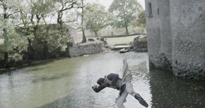Knight jumping out of castle window and into moat - slow motion