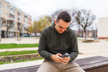 A man using his phone to talk or send messages outside in the city during the day	