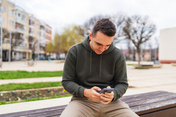 Obraz premium A man using his phone to talk or send messages outside in the city during the day 