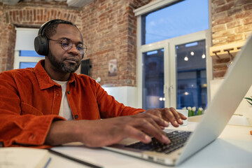 African american young man typing on laptop and looking serious