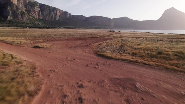 Aerial view drone of sea cost. Flying over off road and grass during summer sunset