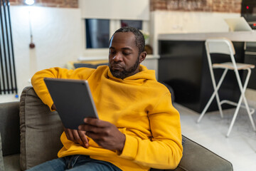 African american man in yellow hoodie with tablet in hands