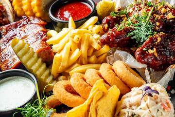 A tantalizing platter of fast food: glazed ribs, crispy fries, onion rings, and dipping sauces....