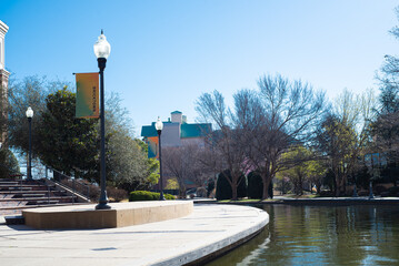 Light pole banner and buildings along Bricktown canal with curved sidewalk pathway, riverside...