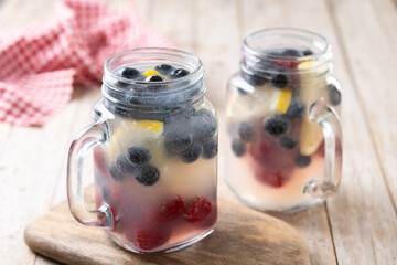 Fresh berry drink with blueberries and raspberries and lemon on wooden table. 
