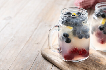 Fresh berry drink with blueberries and raspberries and lemon on wooden table. Copy space