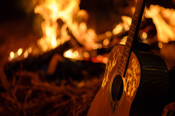 plays guitar close up view of a blurry background of a bonfire